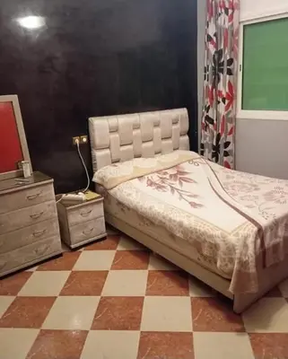 a bedroom with a bed and a checkered floor at Maison zakaria in Meknès