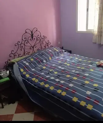 a bed with a blue and yellow comforter in a bedroom at Maison zakaria in Meknès