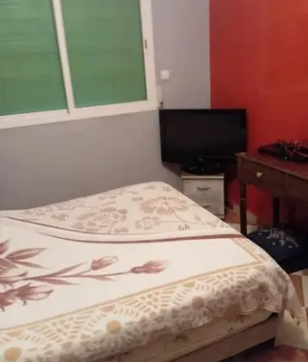 a small bedroom with a bed and a television at Maison zakaria in Meknès