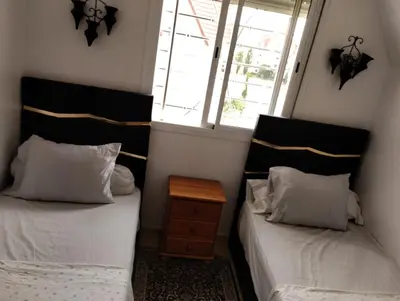 two beds in a small room with a window at Dar Yasmine 3 in Ifrane