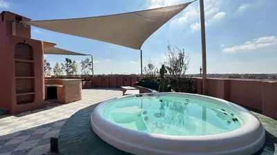 a hot tub on a patio with an umbrella at Rooftop au centre de Guéliz in Oulad Akkou