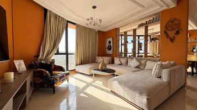a living room with orange walls and a couch and chairs at Rooftop au centre de Guéliz in Oulad Akkou