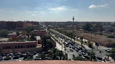 a city with a lot of cars parked in a parking lot at Rooftop au centre de Guéliz in Oulad Akkou