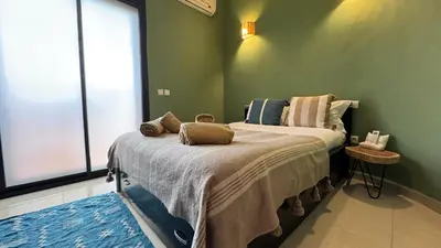 a green bedroom with a bed with two pillows on it at Rooftop au centre de Guéliz in Oulad Akkou