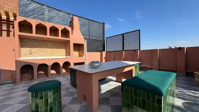 a patio with a table and two green stools at Rooftop au centre de Guéliz in Oulad Akkou