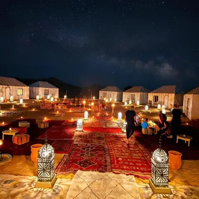 a group of people walking around a courtyard at night at Saba Queen Camp in Khamliya
