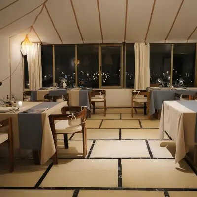 a dining room with tables and chairs and windows at Saba Queen Camp in Khamliya