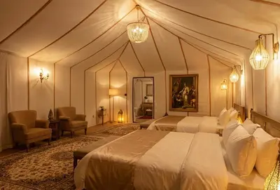 a large bedroom with two beds and chairs in it at Saba Queen Camp in Khamliya