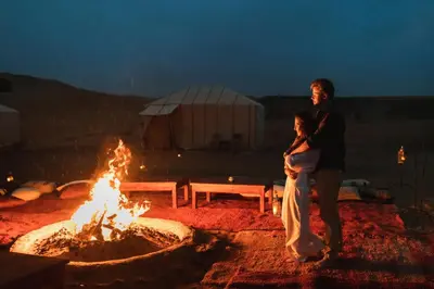 a man and a woman standing in front of a fire at Saba Queen Camp in Khamliya