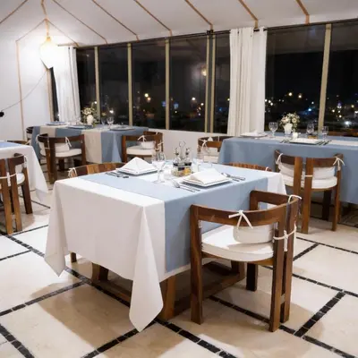 a dining room with tables and chairs and windows at Saba Queen Camp in Khamliya
