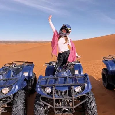 a woman standing on a quad bike in the desert at Sunny Luxury Camp in Merzouga