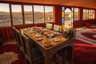 a table with plates and glasses on it in a room with windows at Chams Luxury Camp in Lac Yasmins
