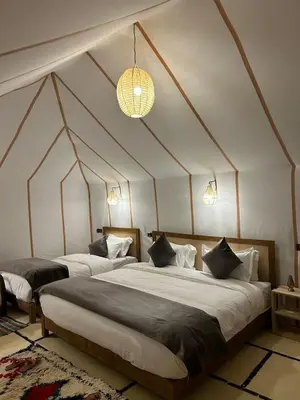 two large beds in a room with a tent at Moonrise Luxury Camp in Merzouga