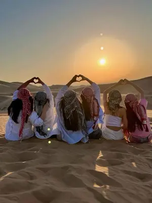 a group of women sitting in the desert with their hands in the sand at Moonrise Luxury Camp in Merzouga