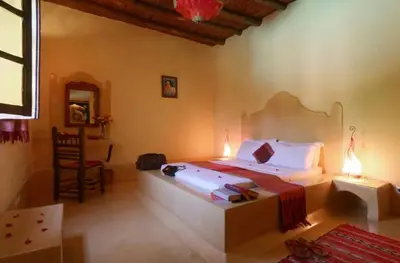 a bedroom with a bed and a table and a chair at Riad Souiguia in Oulad Zbir