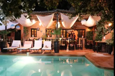 a swimming pool with white chairs and a restaurant at Riad Souiguia in Oulad Zbir