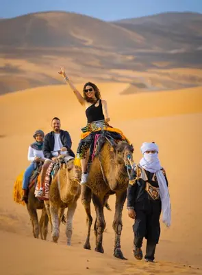 a group of people riding on camels in the desert at Desert Luxe Camp in Merzouga