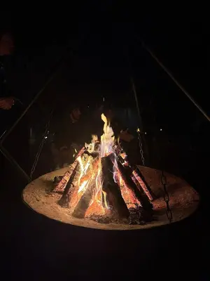 a fire pit in the dark with people around it at Desert Luxe Camp in Merzouga