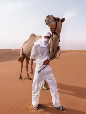 a man with a camel in the desert at Desert Luxe Camp in Merzouga