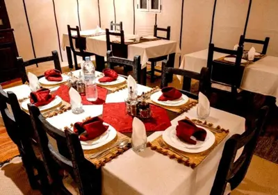 a dining room with white tables and chairs with red napkins at Dunes Light Luxury camp in Merzouga