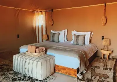 a bedroom with a large bed and two lamps at Dunes Light Luxury camp in Merzouga