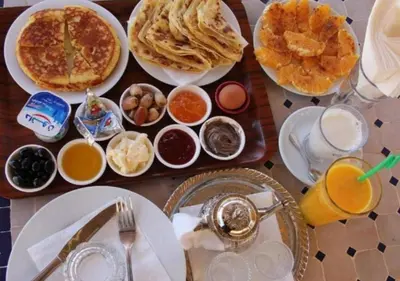 a table with plates of breakfast food and drinks at Dunes Light Luxury camp in Merzouga