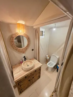 a bathroom with a sink and a mirror and a toilet at Erg Palace Luxury Camp in Merzouga