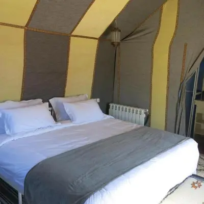 a bedroom with a large bed in a tent at Erg Palace Luxury Camp in Merzouga