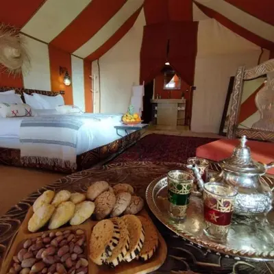 a room with a bed and a table with food at Erg Palace Luxury Camp in Merzouga