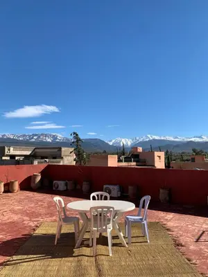 a table and chairs on a patio with mountains in the background at Villa ourika in Aghmat