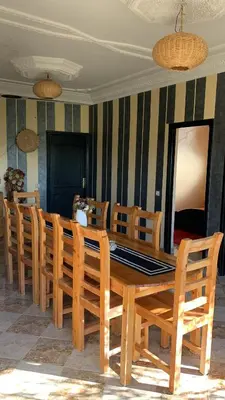 a dining room with a wooden table and chairs at Villa ourika in Aghmat