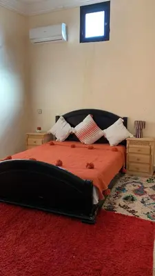 a bedroom with a large bed with a red rug at Villa ourika in Aghmat