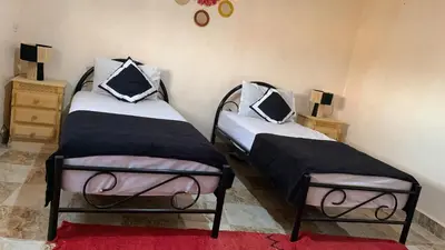two twin beds in a room with a red rug at Villa ourika in Aghmat