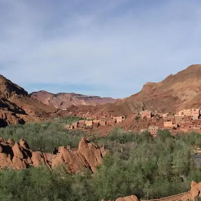 a village in the desert with mountains in the background at Red Rocks Guest House in Oulad Akkou