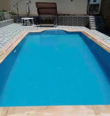 a large blue swimming pool with a table and a chair at Appartement familial 110 m2 in Meknès