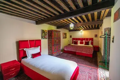 a bedroom with two red beds and a red couch at Riad Fez social club in Fès