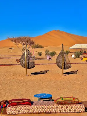 a desert with rocks and a blue table in the desert at Desert Paradise Lodging in Merzouga