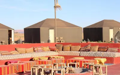 a group of tables and chairs on a stage at Desert Paradise Lodging in Merzouga
