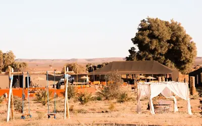 a building with a white curtain in a field at Desert Paradise Lodging in Merzouga