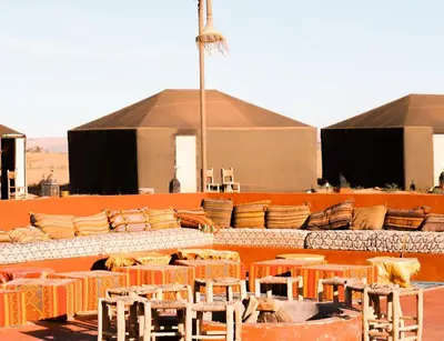 a group of tables and chairs in front of a building at Desert Paradise Lodging in Merzouga