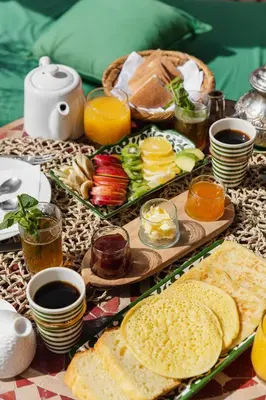 a table with two trays of food and cups of coffee at Desert Paradise Lodging in Merzouga