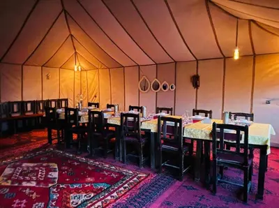 a room with tables and chairs in a tent at Merzouga Luxury Camp & Desert Activities in Merzouga