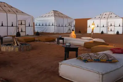 a room with tents and couches in the desert at Merzouga Luxury Camp & Desert Activities in Merzouga