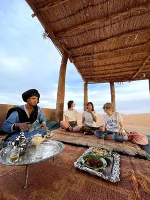 a group of people sitting on the beach at Camp Nuyum in Ksiba