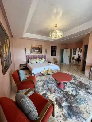 a bedroom with a bed and a table and chairs at VIilla SOLANA Domaine LAMRAH in Oulad Snaguia
