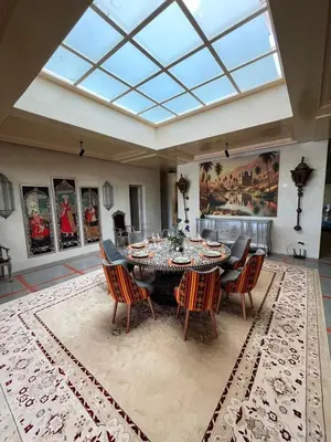 a dining room with a table and chairs on a rug at VIilla SOLANA Domaine LAMRAH in Oulad Snaguia