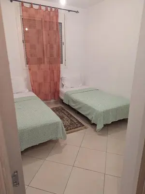 two beds sitting in a room with a shower at Apartment in Agadir in Oulad Akkou