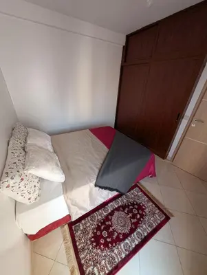 a small bedroom with a bed with two rugs on it at Apartment in Agadir in Oulad Akkou