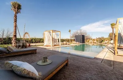 a swimming pool with a table and a couch next to it at villa Bohème Chic in Had Abdallah Rhiat
