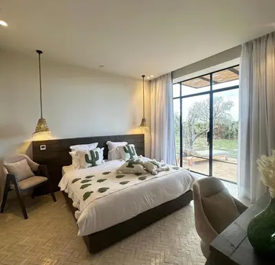 a bedroom with a large bed and a chair at villa Bohème Chic in Had Abdallah Rhiat
